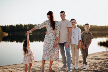 A family of five enjoys a serene lakeside vacation at sunset, capturing precious moments together.